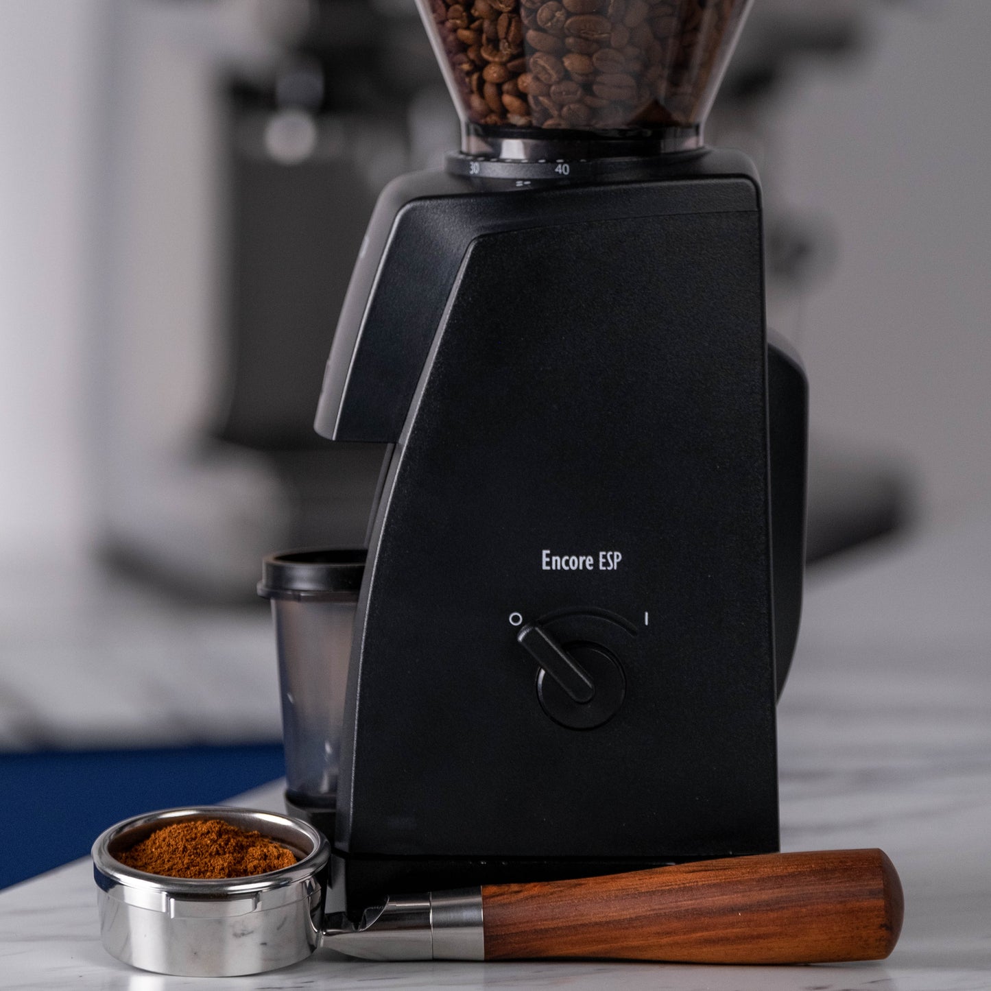 Coffee grinder with coffee beans and ground coffee on a marble surface