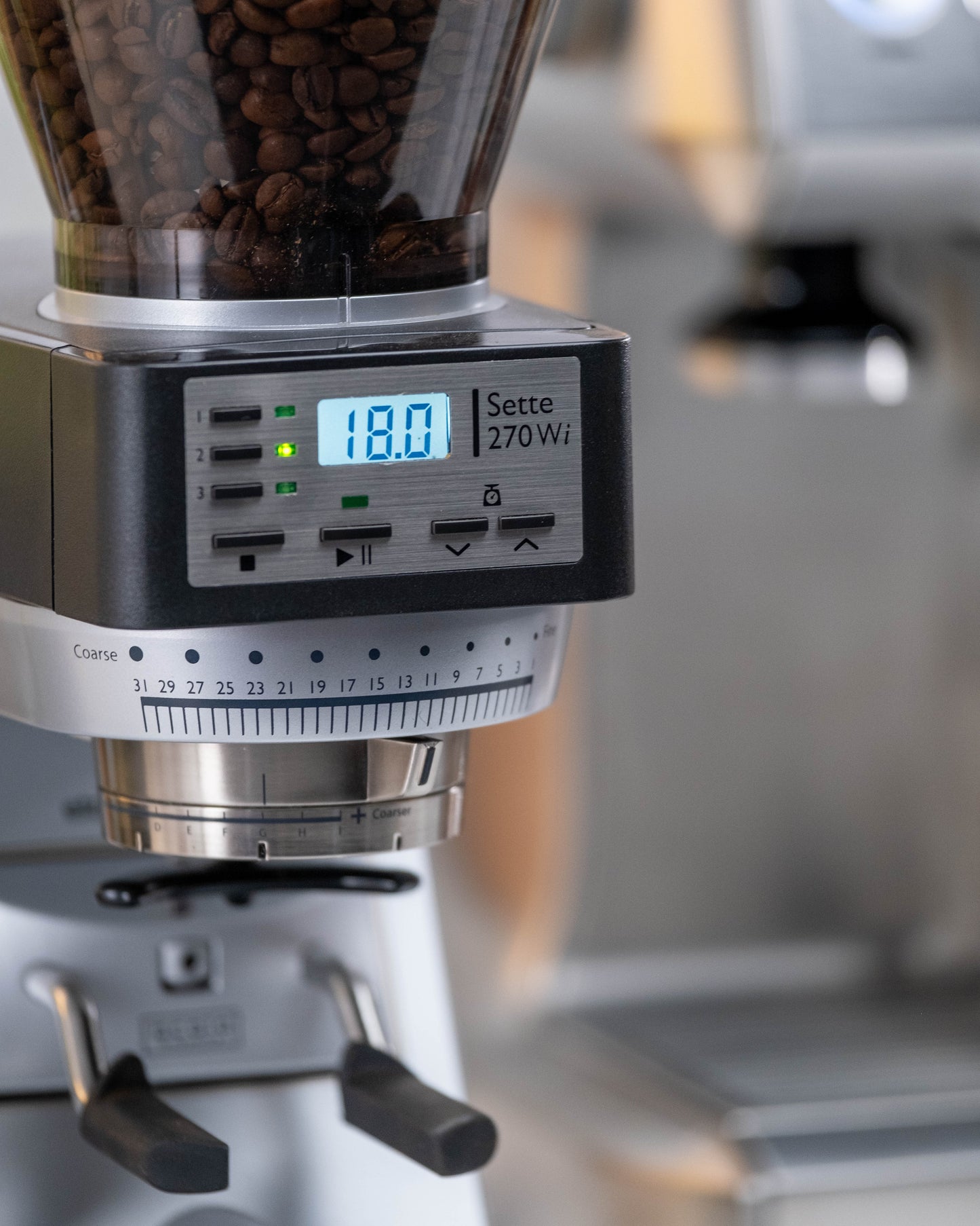 Coffee grinder with digital display showing settings, blurred background