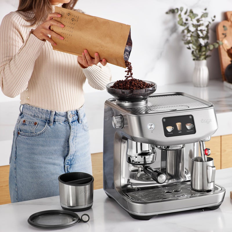 Woman pouring coffee beans into a sage espresso machine.